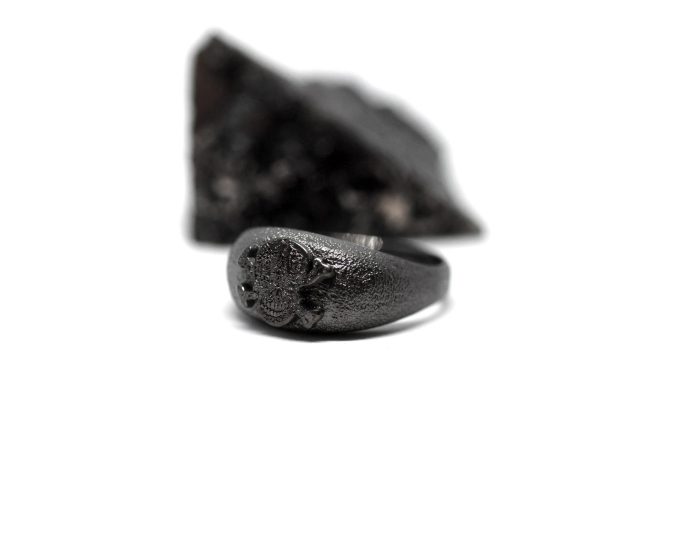 Ανδρικό δαχτυλίδι από ασήμι 925 βαθμών που έχει δεχθεί μαύρη επιπλατίνωση. Το δαχτυλίδι φέρει ένθετο έντεχνο χαρακτικό σχέδιο με νεκροκεφαλή. Σχεδιασμένο για τη συλλογή Θυμήσου Σώμα