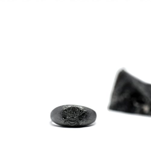 Ανδρικό δαχτυλίδι από ασήμι 925 βαθμών που έχει δεχθεί μαύρη επιπλατίνωση. Το δαχτυλίδι φέρει ένθετο έντεχνο χαρακτικό σχέδιο με νεκροκεφαλή. Δημιουργία από τη συλλογή ''Θυμήσου Σώμα''