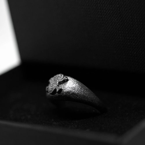 Ανδρικό δαχτυλίδι από ασήμι 925 βαθμών που έχει δεχθεί μαύρη επιπλατίνωση. Το δαχτυλίδι φέρει ένθετο έντεχνο χαρακτικό σχέδιο με νεκροκεφαλή. Μέρος για τη συλλογή ''Θυμήσου Σώμα''