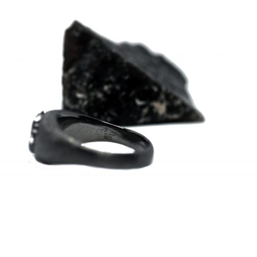 Ανδρικό δαχτυλίδι από ασήμι 925 βαθμών που έχει δεχθεί μαύρη επιπλατίνωση. Το δαχτυλίδι φέρει ένθετο έντεχνο χαρακτικό σχέδιο με νεκροκεφαλή. Κομμάτι της συλλογής ''Θυμήσου Σώμα''