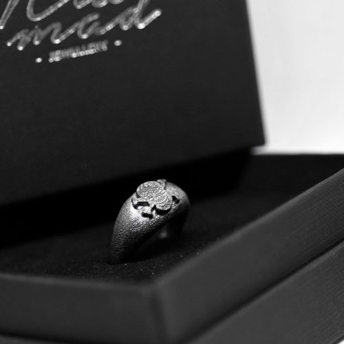 Ανδρικό δαχτυλίδι από ασήμι 925 βαθμών που έχει δεχθεί μαύρη επιπλατίνωση. Το δαχτυλίδι φέρει ένθετο έντεχνο χαρακτικό σχέδιο με νεκροκεφαλή. Από τη συλλογή ''Θυμήσου Σώμα''