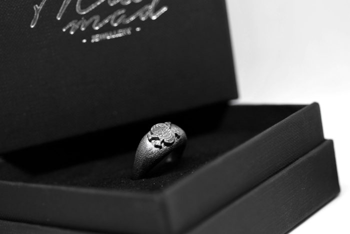 Ανδρικό δαχτυλίδι από ασήμι 925 βαθμών που έχει δεχθεί μαύρη επιπλατίνωση. Το δαχτυλίδι φέρει ένθετο έντεχνο χαρακτικό σχέδιο με νεκροκεφαλή. Από τη συλλογή ''Θυμήσου Σώμα''